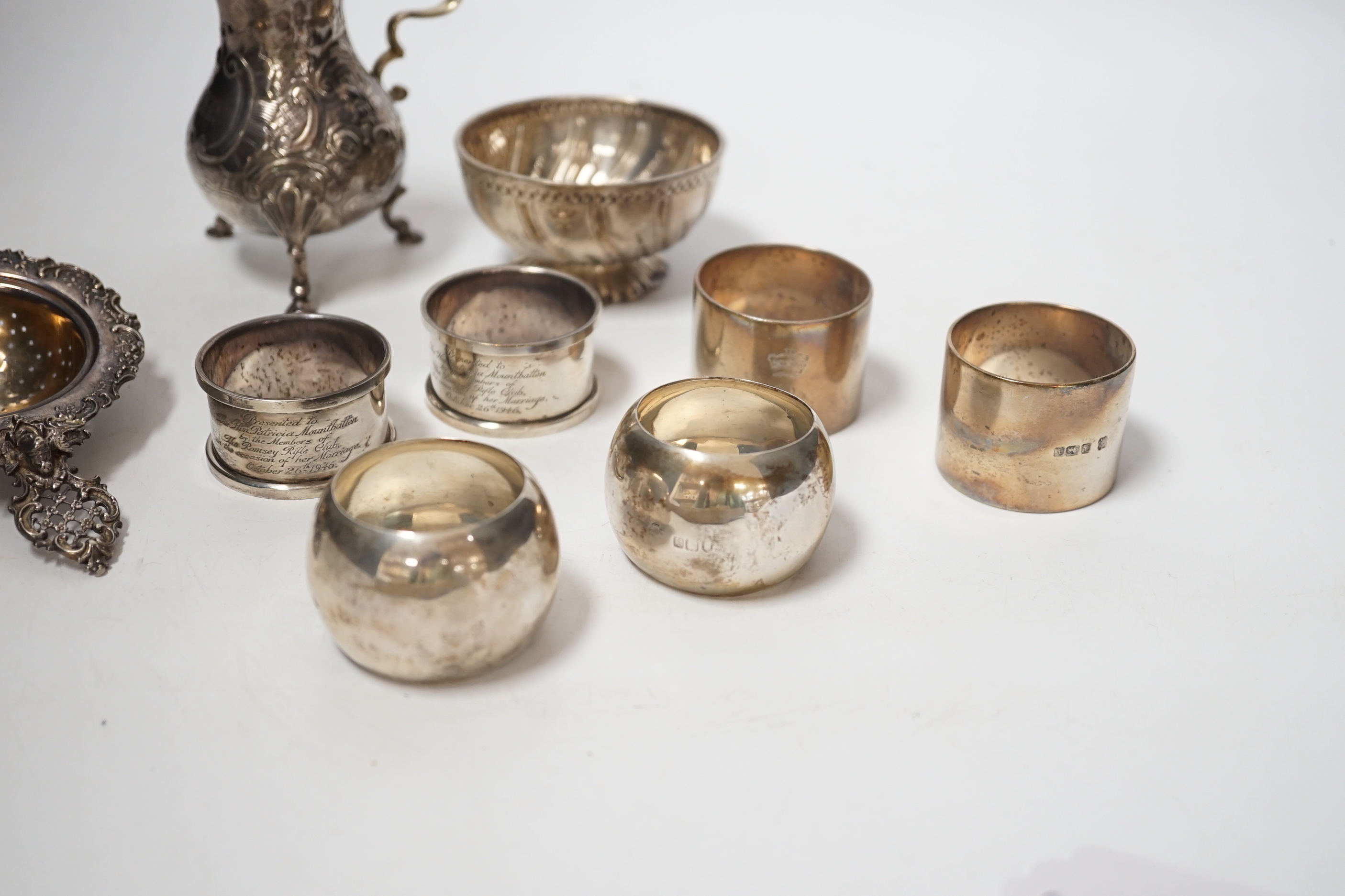 Sundry silver including six silver napkin rings, an 800 standard tea strainer and a white metal bowl and cream jug.